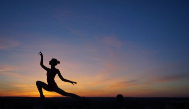 Dans eden dansçı gün batımına karşı havada yarılır.