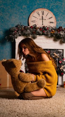 Noel süslemeli stüdyoda şöminenin yanında poz veren güzel esmer genç bir kadın. 