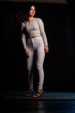 Saçları topuz şeklinde olan genç bayan kollarını kavuşturup yukarı bakıyor. Gri elbiseli, ısıran dudakları olan, arzularını düşünen kaprisli kadın manken. Hayal dünyası konsepti