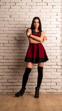 Koyu renk saçlı, kırmızı elbiseli, karanlık stüdyoda poz veren genç ve seksi bir kadın..