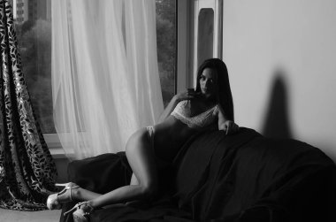 İç çamaşırlarıyla kanepede poz veren sevimli, çekici, çekici bir kızın portresi. 