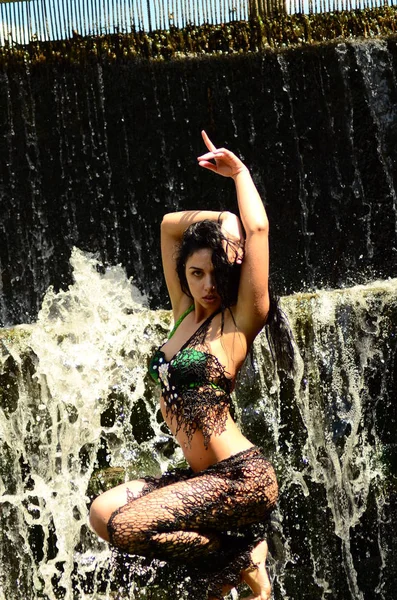 Young brunette model posing against a waterfall — Stock Photo, Image