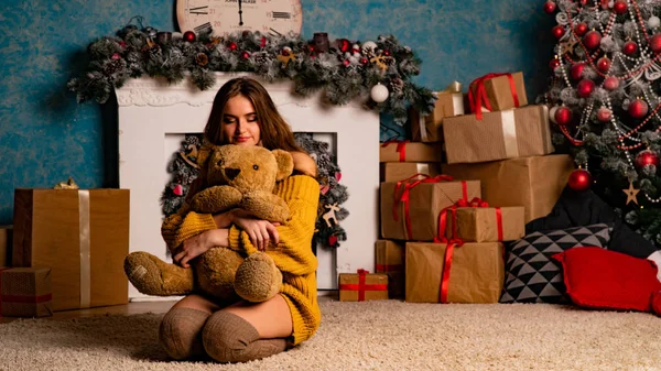 Noel süslemeli stüdyoda şöminenin yanında poz veren güzel esmer genç bir kadın. 