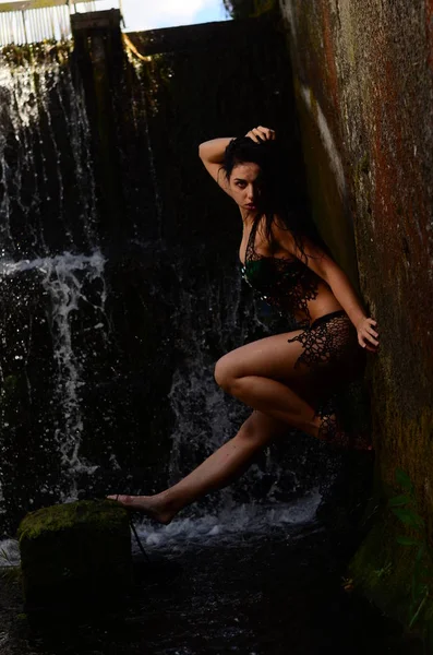 Jeune modèle brune posant contre une cascade — Photo