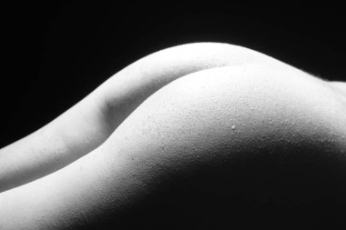 Siyah ve beyaz güzel kadın vücudu. Üzerinde gölgesi olan zarif çıplak bir kadının moda sanat stüdyosu portresi. Kadın midesi siyah arka planda izole edilmiş. Erotik poz düşük tuş atışı.