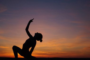 Dans eden dansçı gün batımına karşı havada yarılır.