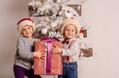 Ukraine, 28.01.2020: christmas and new year concept. happy young kids in santa claus clothes with a gift box