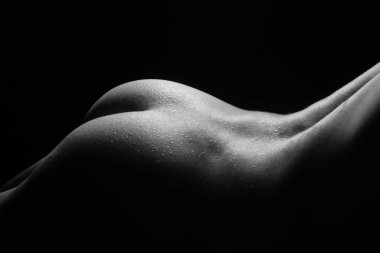 Siyah ve beyaz güzel kadın vücudu. Üzerinde gölgesi olan zarif çıplak bir kadının moda sanat stüdyosu portresi. Kadın midesi siyah arka planda izole edilmiş. Erotik poz düşük tuş atışı.