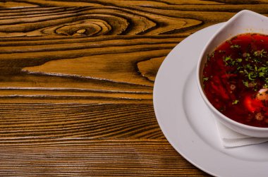 Çorba, ekşi kremalı borç, arka planda boncuk ve turşu. Borç beyaz bir tabakta, ekmek dilimleri ahşap bir kesme tahtasında, turşular ahşap bir tabakta..