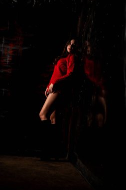 Koyu arkaplanda kırmızı kazaklı, güzel, çıplak kadın.   