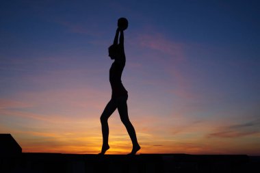 Dans eden dansçı gün batımına karşı havada yarılır.