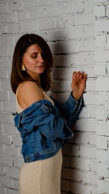 esmer kız yeşil bir ceket ve beyaz tuğla duvarın yanında sutyen standları