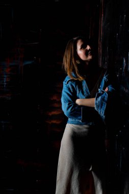 esmer kız yeşil bir ceket ve beyaz tuğla duvarın yanında sutyen standları.