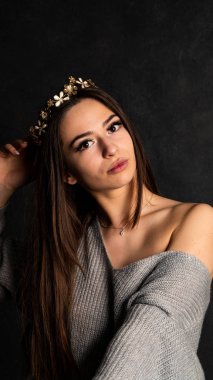 Stüdyoda siyah bir arka planda duran kolları olan güzel gri elbiseli seksi bir genç. 