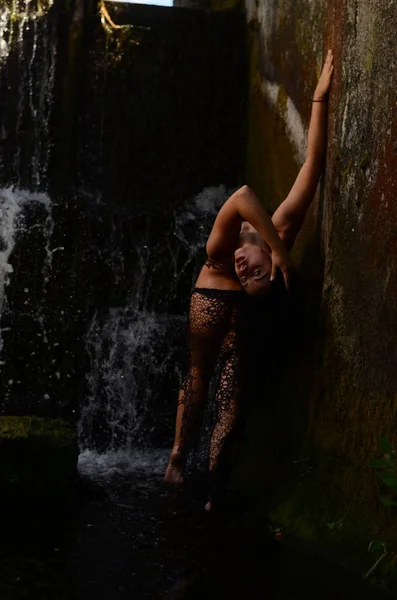 Молодая брюнетка позирует против водопада — стоковое фото