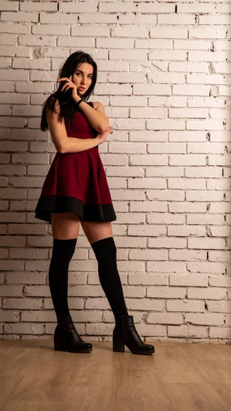 可愛いです若いですセクシーモデル女性とともに黒髪で赤いドレスポーズでダークスタジオ — ストック写真