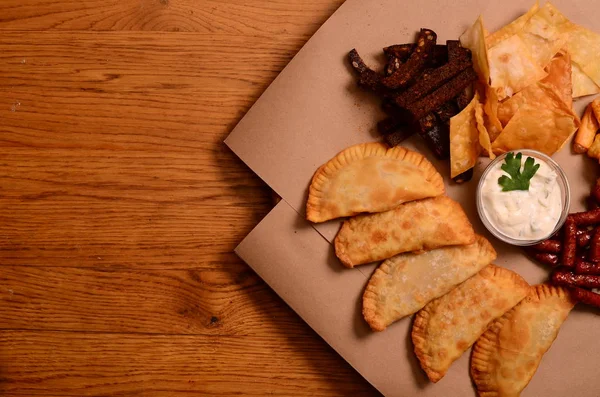 Tortilla chips gegarneerd met gemalen rundvlees, gesmolten kaas, paprika 's en koriander bladeren in plaat op houten tafel — Stockfoto