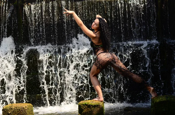 Joven modelo morena posando contra una cascada — Foto de Stock