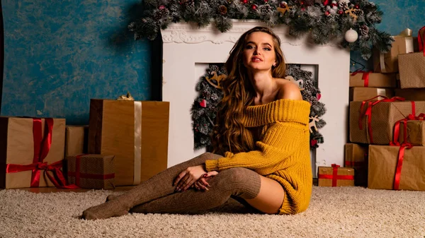 Noel süslemeli stüdyoda şöminenin yanında poz veren güzel esmer genç bir kadın. 