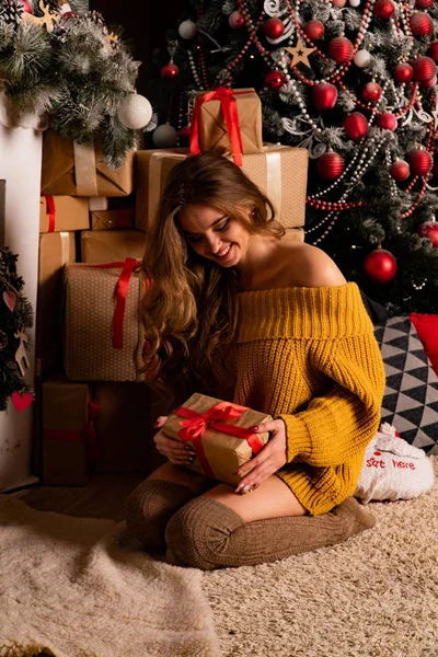 Noel süslemeli stüdyoda şöminenin yanında poz veren güzel esmer genç bir kadın. 