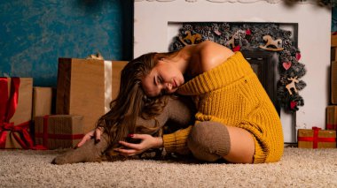 Noel süslemeli stüdyoda şöminenin yanında poz veren güzel esmer genç bir kadın. 