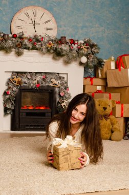 Noel süslemeli stüdyoda şöminenin yanında poz veren çekici esmer kadın.  