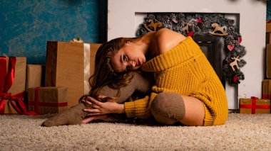 Noel süslemeli stüdyoda şöminenin yanında poz veren güzel esmer genç bir kadın. 