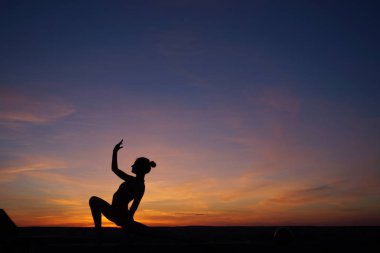 Dans eden dansçı gün batımına karşı havada yarılır.