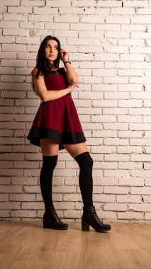 Koyu renk saçlı, kırmızı elbiseli, karanlık stüdyoda poz veren genç ve seksi bir kadın..