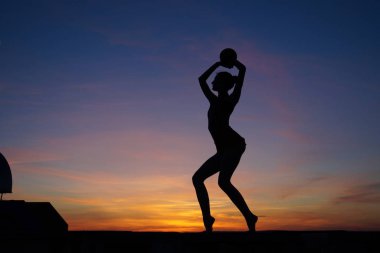 Dans eden dansçı gün batımına karşı havada yarılır.