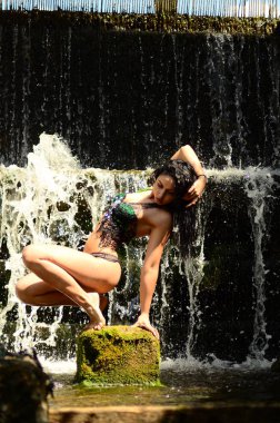 Genç esmer model bir şelale karşı poz