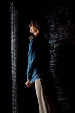 esmer kız yeşil bir ceket ve beyaz tuğla duvarın yanında sutyen standları.