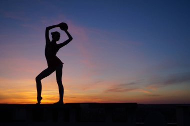 Dans eden dansçı gün batımına karşı havada yarılır.