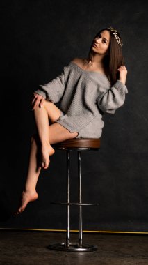 Stüdyoda siyah bir arka planda duran kolları olan güzel gri elbiseli seksi bir genç. 