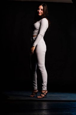 Saçları topuz şeklinde olan genç bayan kollarını kavuşturup yukarı bakıyor. Gri elbiseli, ısıran dudakları olan, arzularını düşünen kaprisli kadın manken. Hayal dünyası konsepti