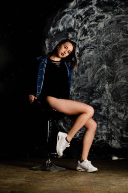 Güzel genç bir kadın karanlık arka planda poz veriyor. 