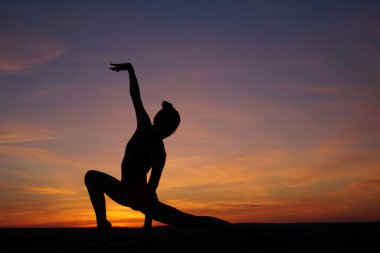 Dans eden dansçı gün batımına karşı havada yarılır.