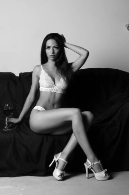 İç çamaşırlarıyla kanepede poz veren sevimli, çekici, çekici bir kızın portresi. 