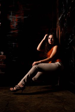 Güzel esmer model, karanlık odada poz veriyor. 