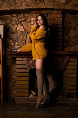 Güzel kız, şöminenin yanında poz veriyor.   