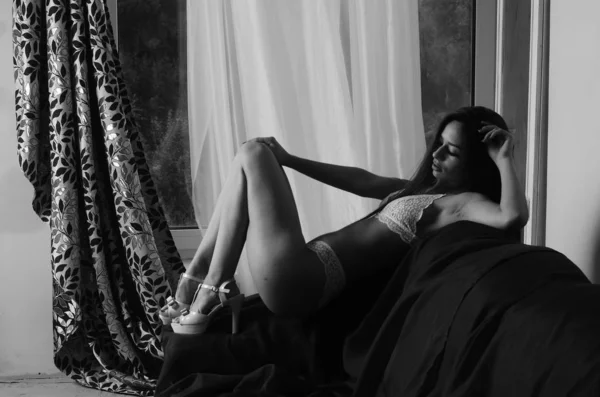 İç çamaşırlarıyla kanepede poz veren sevimli, çekici, çekici bir kızın portresi. 