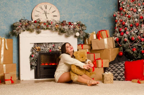 Noel süslemeli stüdyoda şöminenin yanında poz veren çekici esmer kadın.  