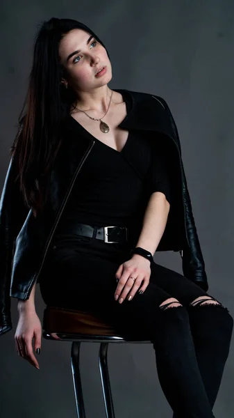 年轻的黑发女子 穿着时髦的衣服 在黑暗的工作室里摆姿势 — 图库照片