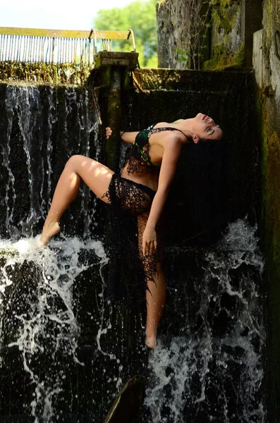 Jeune modèle brune posant contre une cascade — Photo