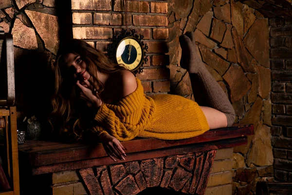 Şöminenin yanında oturan güzel kız. Noel için içi köknar dalları ve oyuncaklarla süslenmiş lüks bir iç mekan.