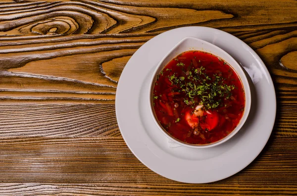 Çorba, ekşi kremalı borç, arka planda boncuk ve turşu. Borç beyaz bir tabakta, ekmek dilimleri ahşap bir kesme tahtasında, turşular ahşap bir tabakta..