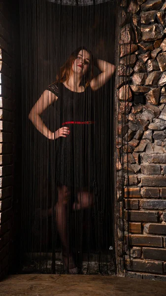Seduce woman posing behind curtains of black threads.