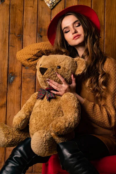 beautiful brunette woman with toy bear posing in wooden studio