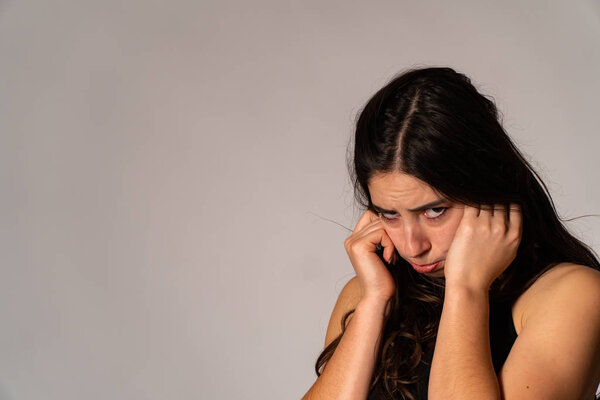 Portrait of disconcerted young woman in light clothes looking aside covering nose with hand isolated on white wall background in studio. People sincere emotions, lifestyle concept. Mock up copy space