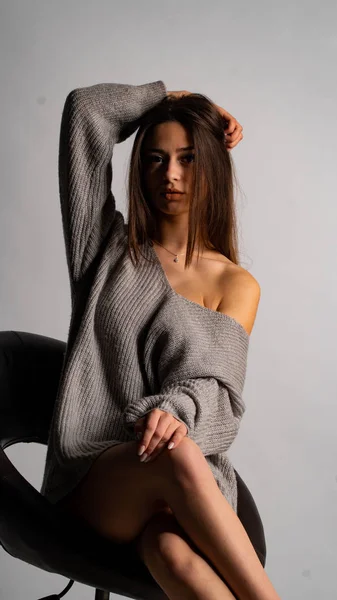 Красива сексуальна дівчина, позує коротку сіру сукню, білий стілець на фоні — стокове фото